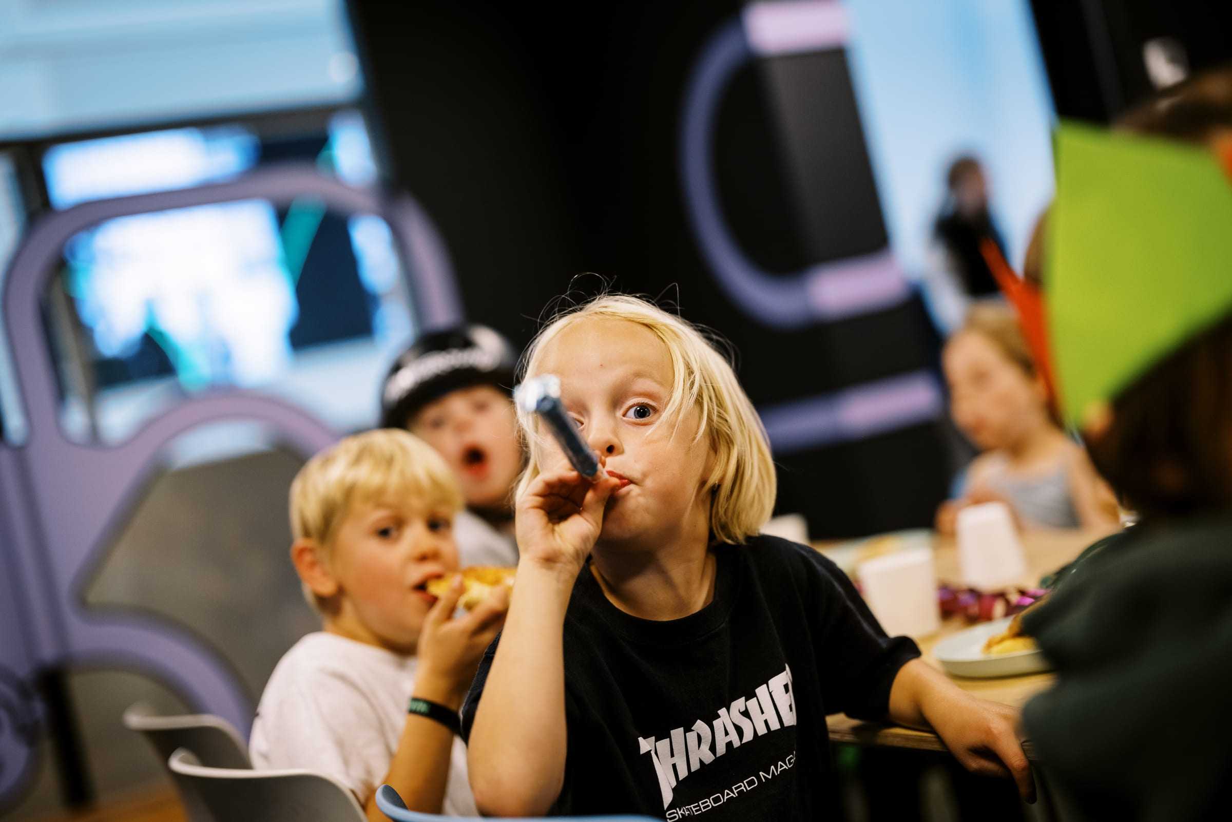 Birthday kids blowing party horns around the cake table