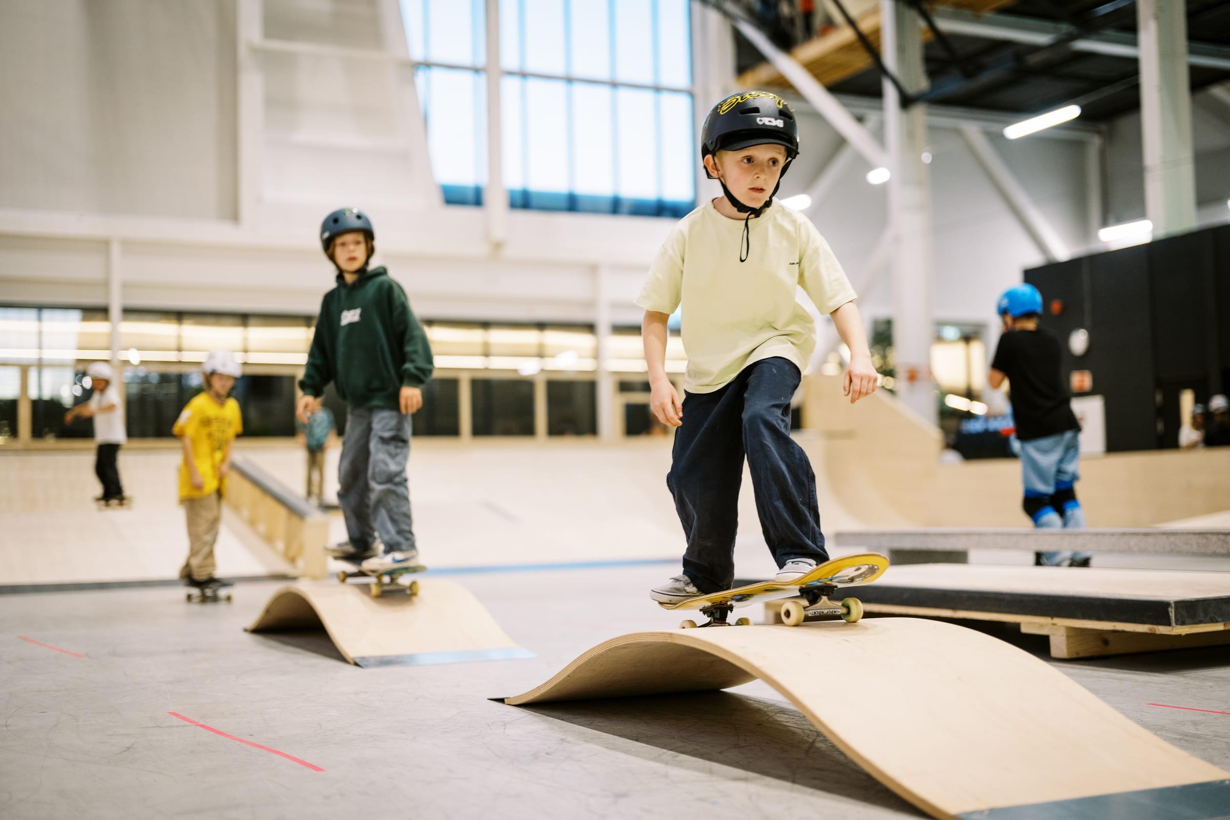 Barn skater på ramper i Playgrounds innendørs skatepark